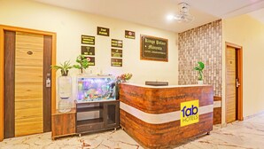A reception desk with a wooden finish and a 'fab hotels' sign, a reception area with a fish tank, and a 'Kings Palace' sign on the wall. - FabHotel Kings Palace Manyata - Near Manyata Tech Park Main Gate (Bangalore)