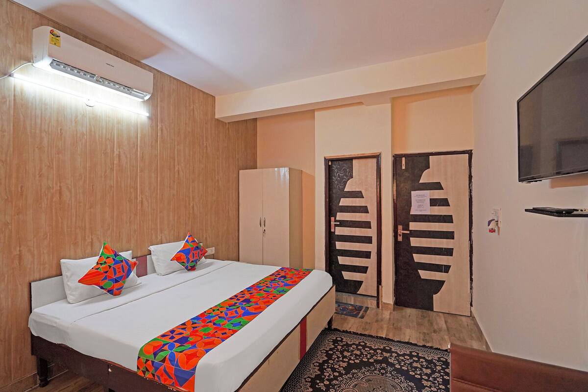 Habitación de hotel con cama, armario, televisor y puerta con diseño decorativo.