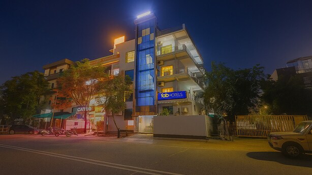 A modern hotel with a prominent 'fabHOTELS' sign, multiple balconies, and a well-lit facade. - Fabhotel Mvr Stay 116 (Noida)