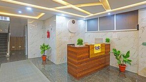 Un mostrador de recepción de hotel con una pared de mármol, un extintor y plantas en macetas.