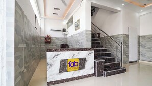 A hotel reception area with a marble counter, a staircase, and geometric patterned walls. - Fabhotel Rk Dham (Vrindavan)