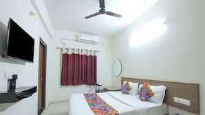 A hotel room with a bed, a TV, an air conditioner, a ceiling fan, and a bedside table with a phone. - FabHotel Golden Grand Inn - Global Village (Bangalore)