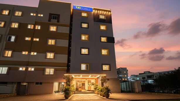 A multi-story hotel with a modern facade, a well-lit entrance, and a landscaped courtyard. - FabHotel Golden Grand Inn - Global Village (Bangalore)