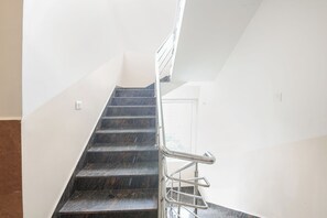 A staircase with a metal handrail leading to a door. - FabHotel Golden Grand Inn - Global Village (Bangalore)
