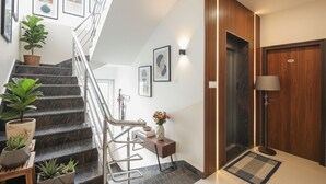 A modern hotel lobby with a marble staircase, a wooden reception desk, and a door marked with the number 61. - FabHotel Golden Grand Inn - Global Village (Bangalore)