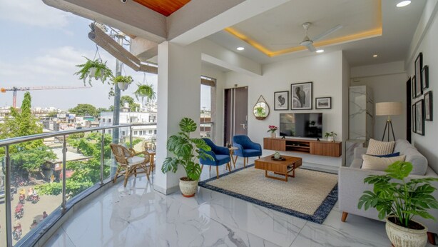 A spacious balcony with a view of the city, a living area with a TV, sofa, and coffee table, and several potted plants. - Fabhotel Keshava executive - Nr Mahadji Shinde chhatri  (Pune)