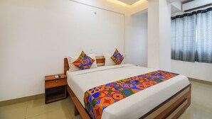 A modern bedroom with a bed, nightstands, and a window with curtains. - Fabhotel Keshava executive - Nr Mahadji Shinde chhatri  (Pune)