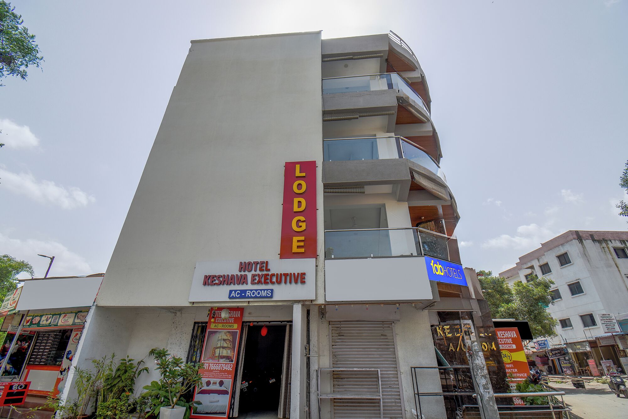A multi-story building with a sign for 'Hotel Keshava Executive' and 'Lodge' indicating it offers rooms and possibly other accommodations.