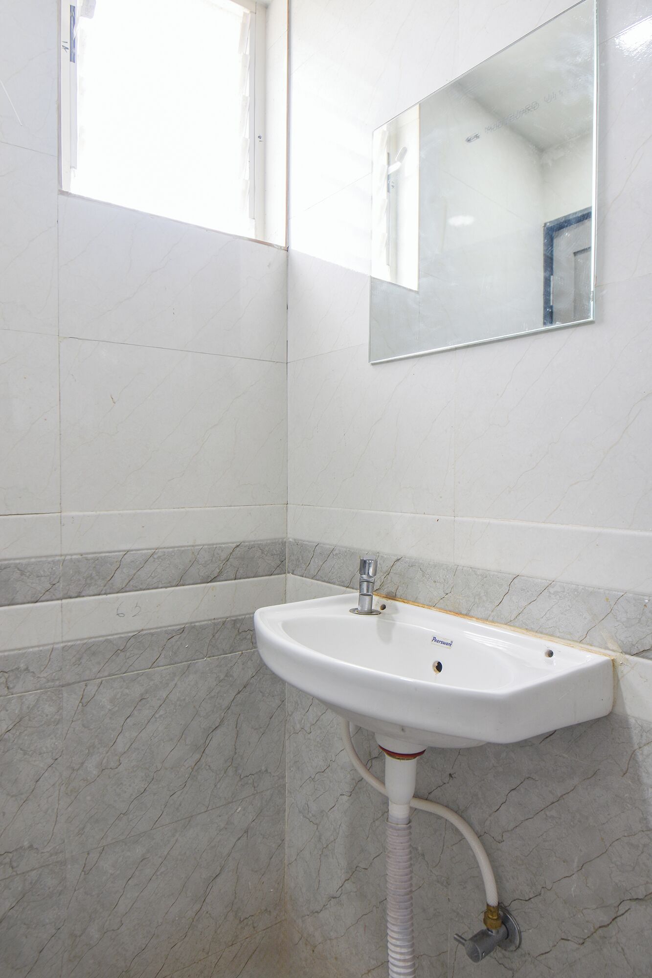 A bathroom with a white sink, a mirror, and marble-patterned walls.