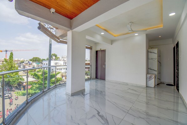 A spacious balcony with a view of the cityscape, a modern interior with a marble floor, and a ceiling fan.