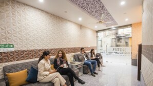 A reception area with a patterned wall, a ceiling fan, and a sign indicating an exit. - FabHotel Golden Comforts (Bengaluru)