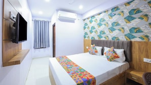 A hotel room with a bed, a TV mounted on the wall, a ceiling fan, and an air conditioning unit. - FabHotel Golden Comforts (Bengaluru)