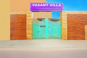 Egy kapuval ellátott bejárat, amelyen egy tábla jelzi: „VASANT VILLA”.