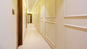 A hotel corridor with a long, narrow layout, featuring a wooden door on the left and a set of double doors on the right. - FabHotel Baba's Inn (New Delhi)