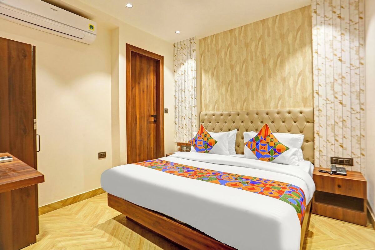 Una habitación de hotel con una cama grande, una mesita de noche de madera, un escritorio y un armario.