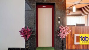 L’entrée d’un hôtel, avec un comptoir d’accueil, un espace d’accueil et un panneau sur le comptoir indiquant « fab hotels ».