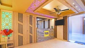 A hotel reception area with a marble counter, wooden paneling, and a ceiling fan. - Fabhotel The Crystal (Kolkata)