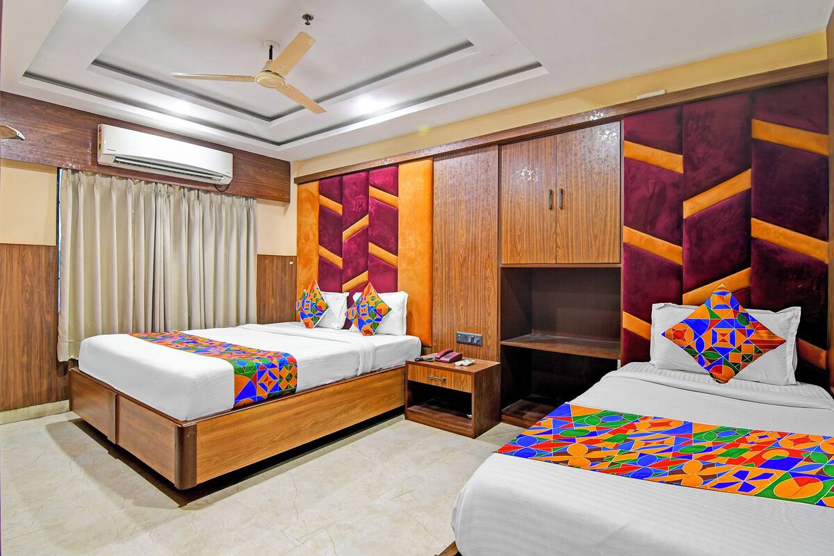 A hotel room with two beds, a wardrobe, a ceiling fan, and an air conditioning unit.