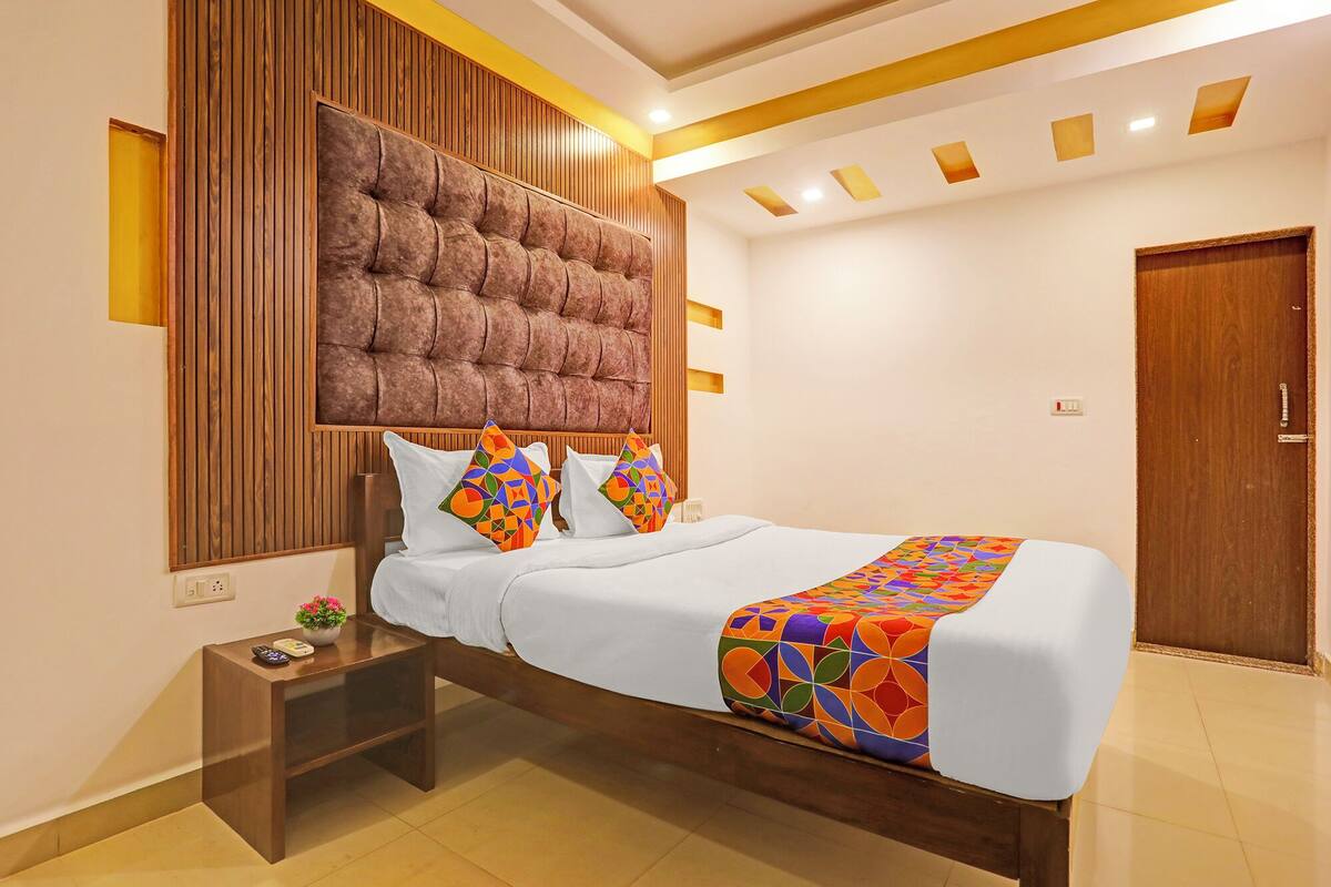 A modern bedroom with a tufted headboard, a wooden nightstand, and a colorful bedspread.