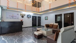 Un vestíbulo de hotel con una recepción, zona de estar y dos puertas.