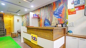 A hotel reception desk with a colorful mural, a sign for 'Lab Hotels', and a green carpeted area. - Fabhotel Galaxy Inn (Mumbai)