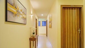 A hallway with a wooden door labeled '204', a tiled floor, and a small table with a vase of flowers. - Fabhotel Galaxy Inn (Mumbai)