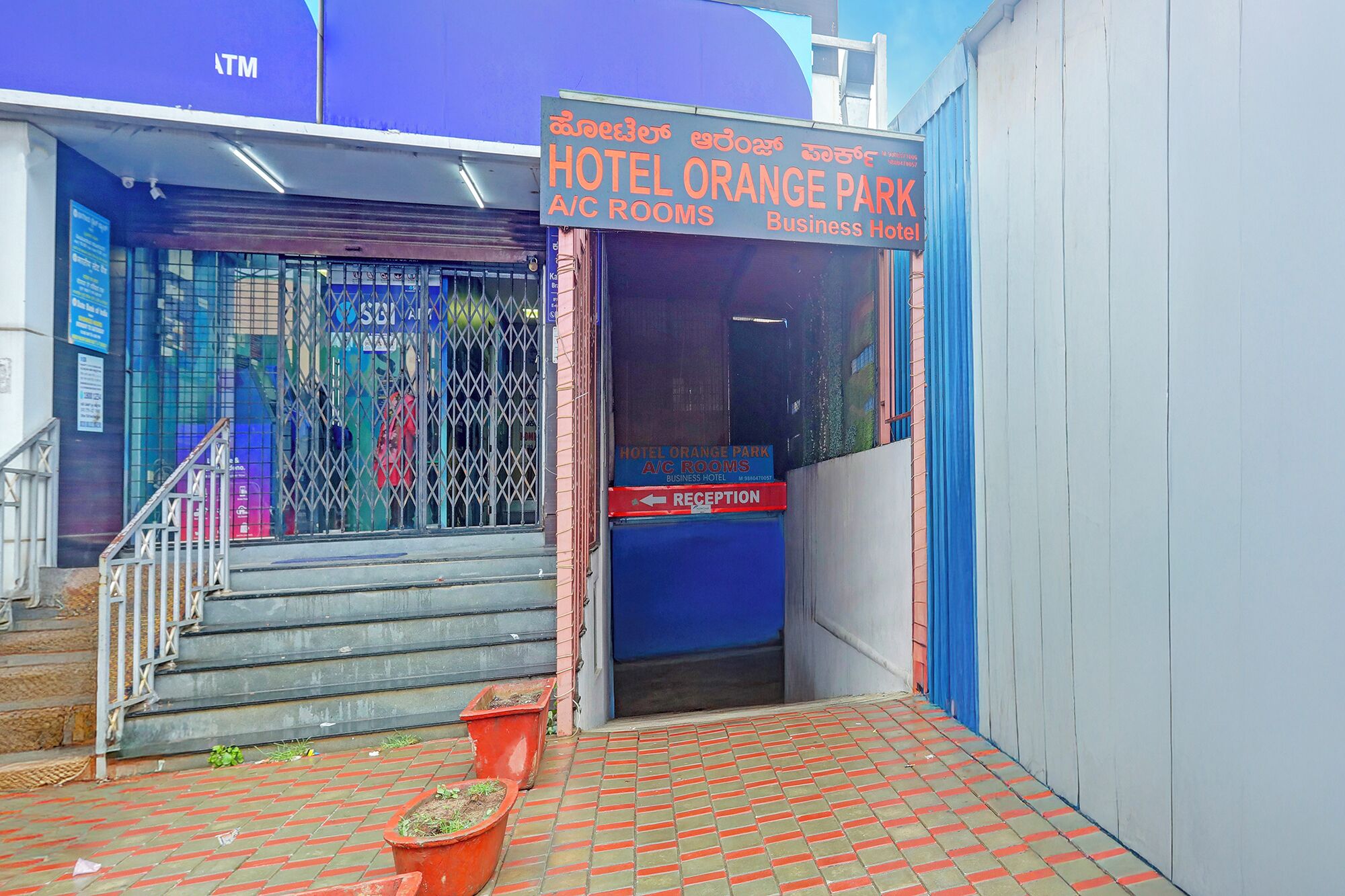 The entrance to Hotel Orange Park A/C Rooms, a business hotel, with a reception sign and a staircase leading up.