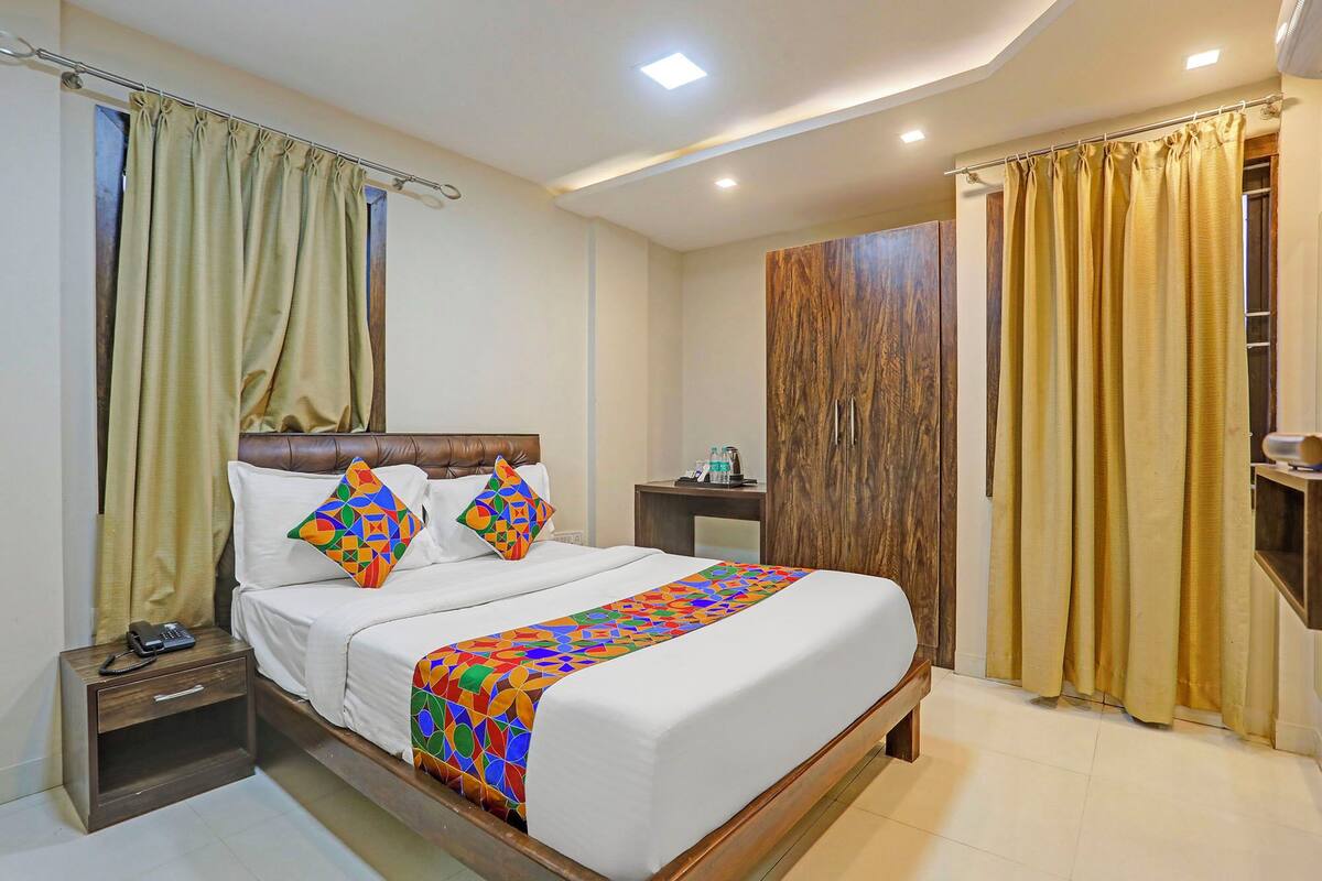 A hotel room with a bed, a nightstand, a wooden wardrobe, and a bathroom with a shower curtain.