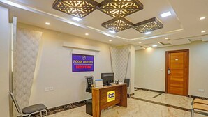 A reception area with a reception desk, a chair, a wall-mounted sign, and a patterned wall. - FabHotel Pooja - Near Bagalur Main Road (Bangalore)