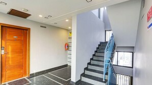 A modern hotel lobby with a wooden door labeled "4001", a blue staircase, and a fire exit sign. - FabHotel Pooja - Near Bagalur Main Road (Bangalore)