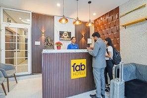 Un mostrador de recepción de hotel con diseño moderno, que incluye un panel de pared de madera, una barra de recepción y un letrero que dice "fab hotels".
