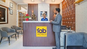 A hotel reception area with a modern design, including a reception desk, seating area, and a wall-mounted display. - Fabhotel Amrit Palace - Opp Skye Corporate park (Indore)