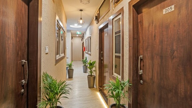 A hallway with wooden doors, numbered 205, and potted plants. - Fabhotel Amrit Palace - Opp Skye Corporate park (Indore)