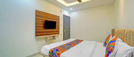 Un dormitorio moderno con cama, ventilador de techo, televisor montado y una puerta.