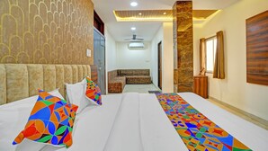 A hotel room with a bed, a sofa, a wardrobe, a ceiling fan, and a window with curtains. - Fabhotel Ss Inn (Indore)