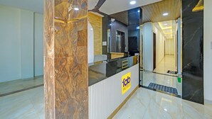 A hotel reception area with a marble column, a reception desk, and a ceiling fan. - Fabhotel Ss Inn (Indore)