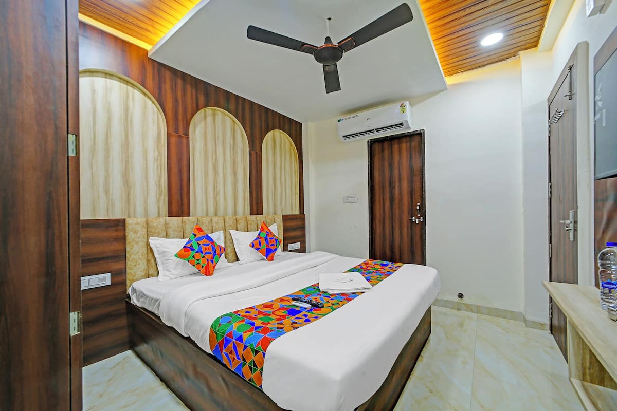 A hotel room with a bed, a ceiling fan, an air conditioning unit, and wooden paneling on the walls.