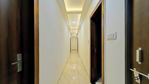 A hotel hallway with a marble floor, recessed ceiling lighting, and wooden doors. - Fabhotel Ss Inn (Indore)