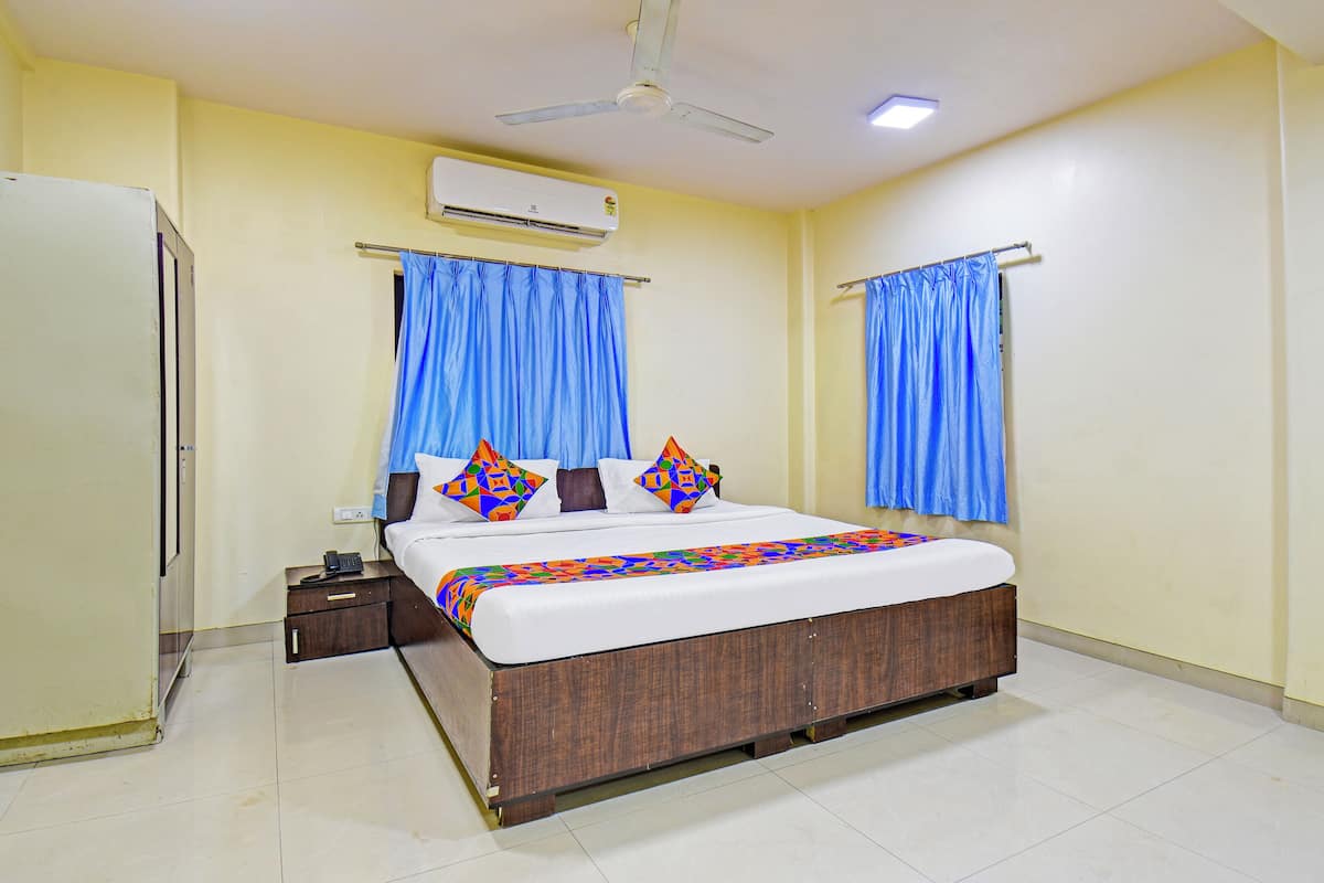 A hotel room with a bed, a wardrobe, a ceiling fan, and an air conditioning unit.
