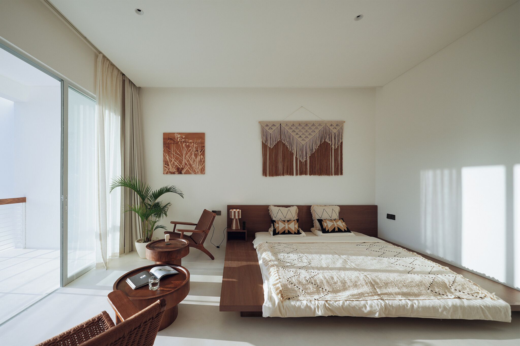 Ein modernes Schlafzimmer mit einem großen Bett, einer Sitzecke mit Couchtisch und Blick auf den Balkon.