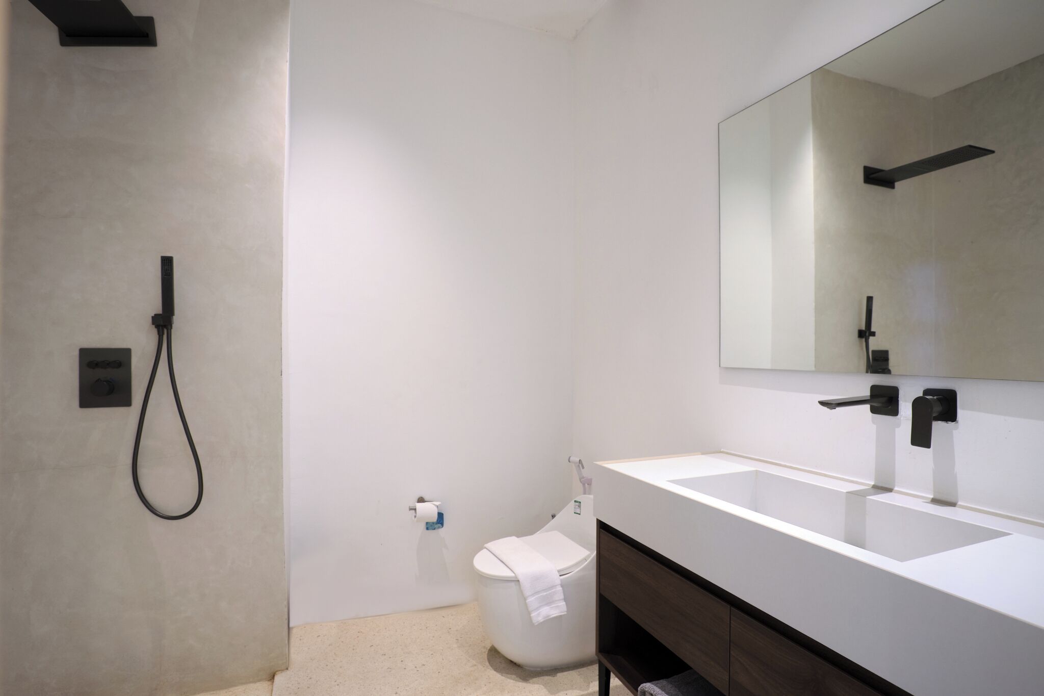 A modern bathroom with a large mirror, a white sink, and a toilet.