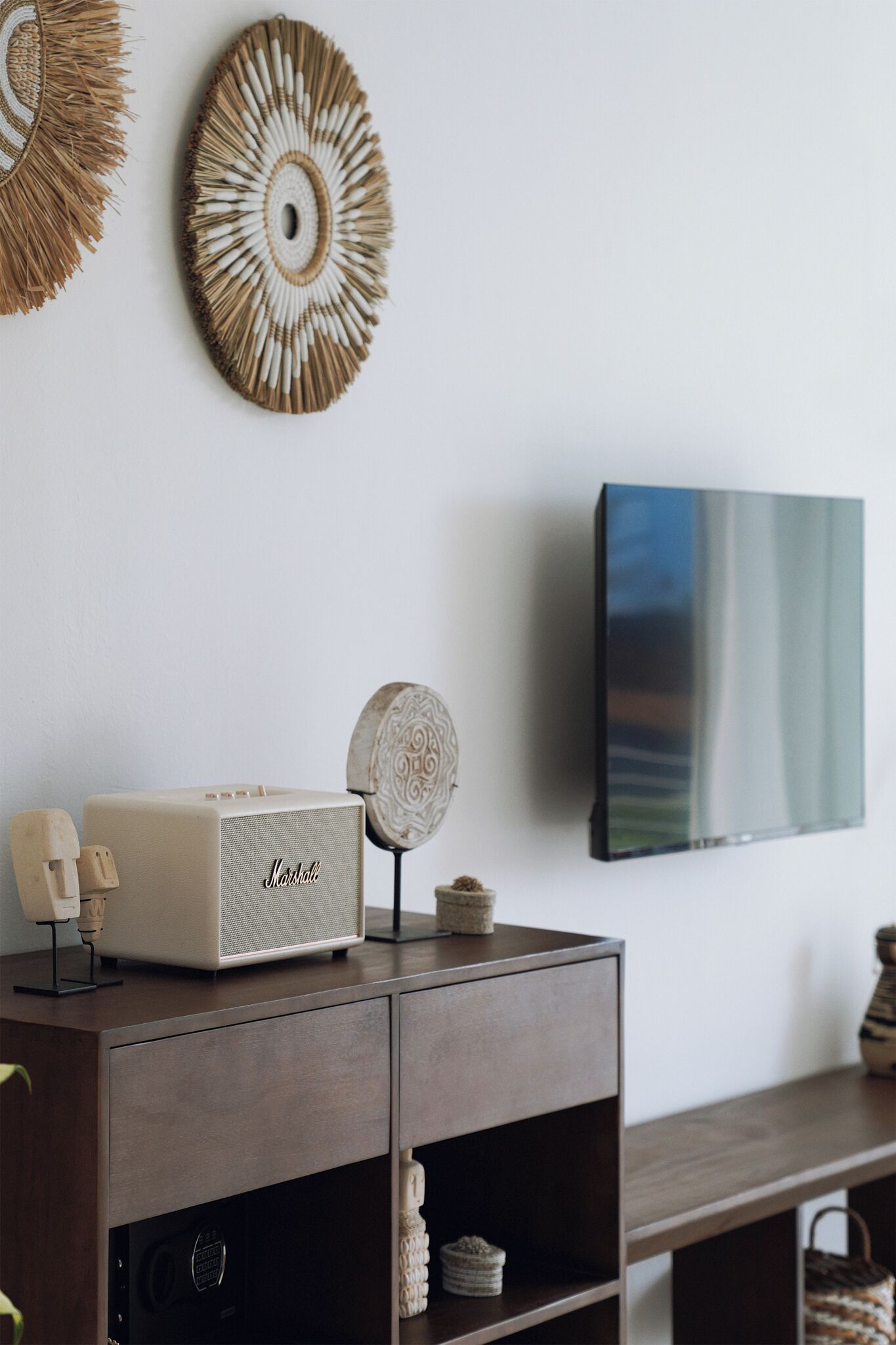 A modern living room with a dark wooden cabinet, a white stereo system, decorative wall art, and a flat-screen TV.
