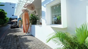 A modern building with a white facade, a glass facade, and a window with a view of greenery. - Serendipity Legian (Legian)