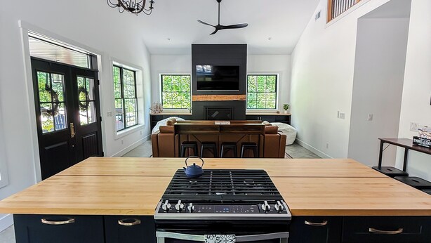 Una cocina moderna con una isla central, horno empotrado y un televisor de pantalla plana sobre la isla.