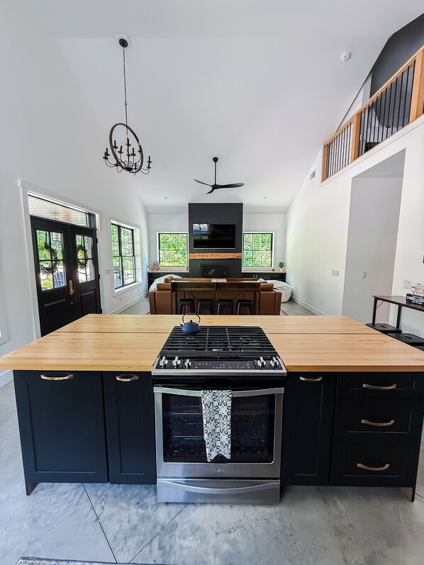 Una cocina moderna con una isla central, horno empotrado y un televisor de pantalla plana sobre la isla.