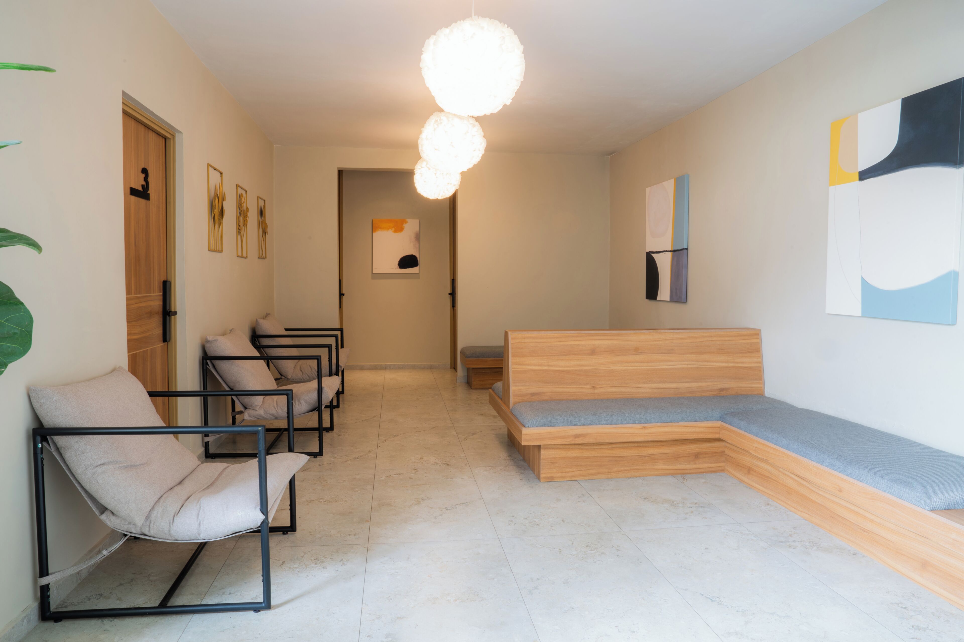 A modern waiting area with a bench, chairs, and artwork on the walls.