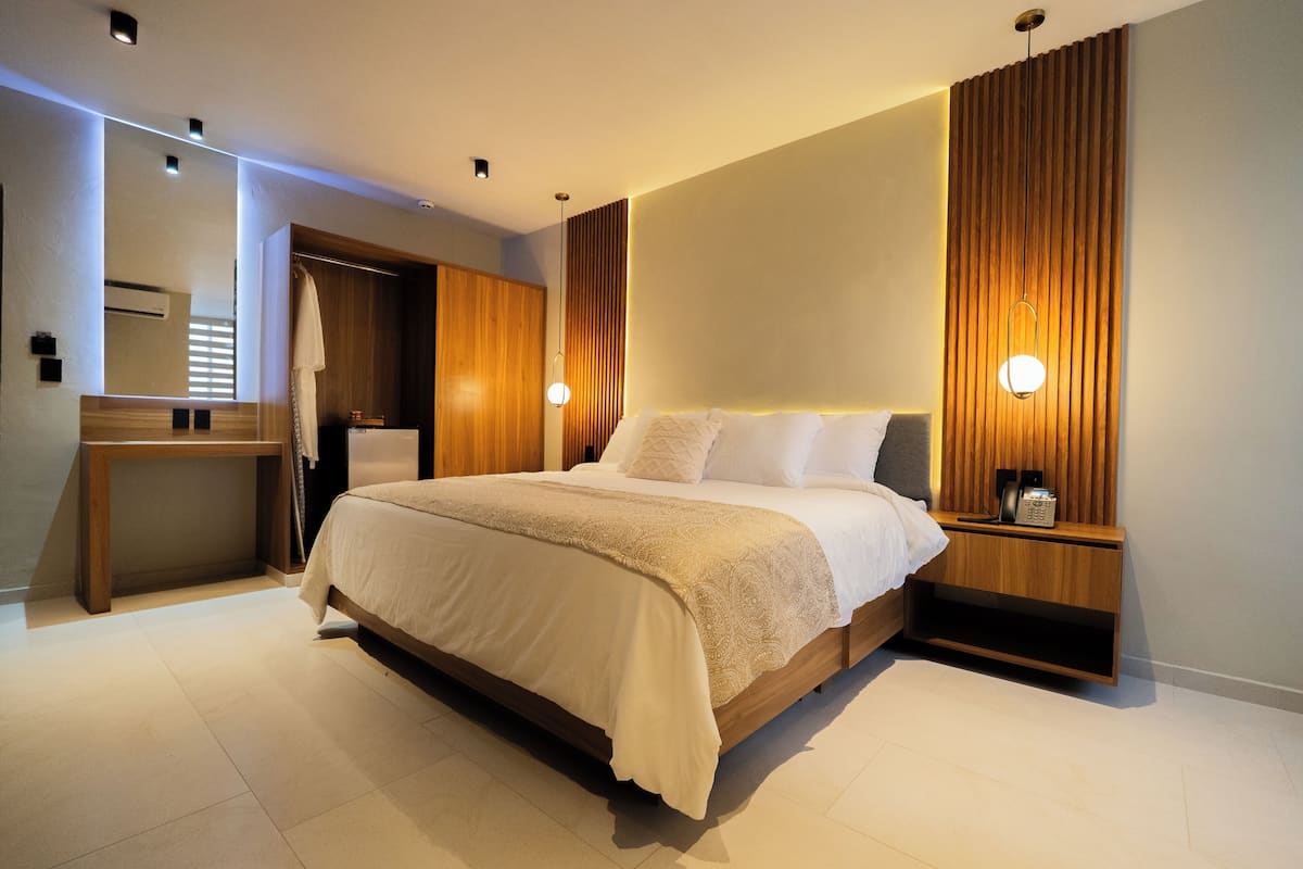 Ein modernes Schlafzimmer mit einem großen Bett, Nachttischen, einem Spiegel und einem Holzkopfende.