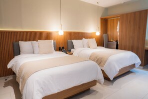 Een hotelkamer met twee bedden, houten hoofdborden, een nachtkastje met een lamp en een kledingkast.