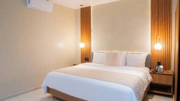 Una habitación de hotel moderna con una cama grande, lámparas de noche, un teléfono y aire acondicionado instalado en la pared.
