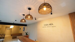 A reception area with a wooden reception desk, three hanging wicker pendant lights, and a wall with the text "CASA MIÁ HOTEL BOUTIQUE". - Casa Mia Hotel Boutique (Zamora)